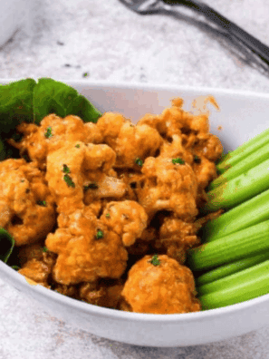 Crispy Buffalo Wild Wings–style cauliflower bites coated in spicy buffalo sauce, served with ranch dressing and celery sticks on a platter.