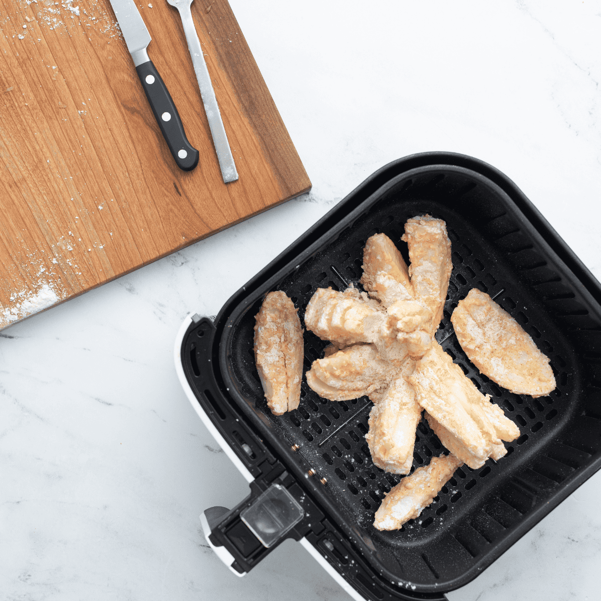 Onion placed cut-side up in air fryer basket, being sprayed with cooking spray for even crisping
