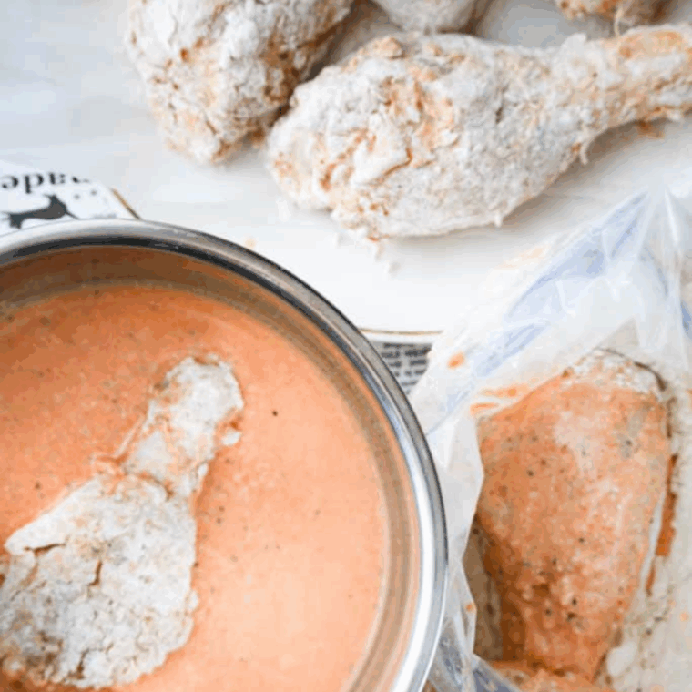 Soaking the fried chicken in the buttermilk mixture.