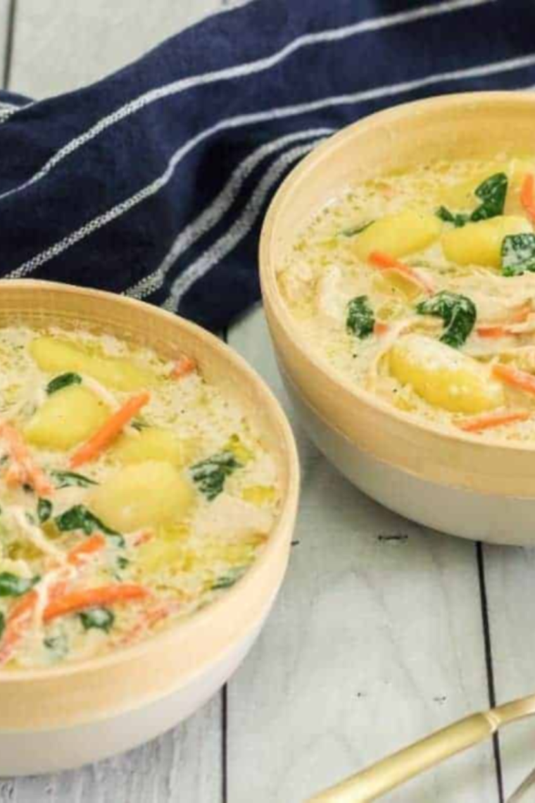 "Finished bowl of Olive Garden Copycat Chicken Gnocchi Soup, garnished with a sprinkle of fresh parsley and grated cheese."