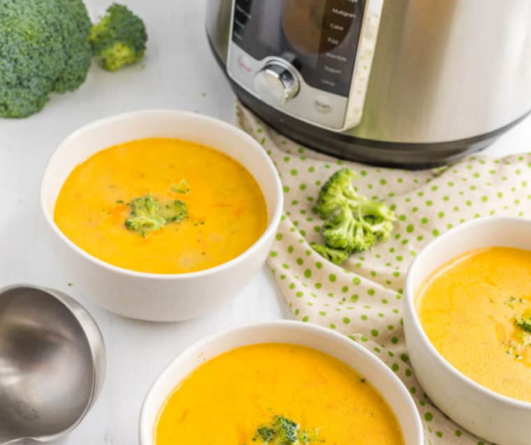 "Finished bowl of Jason's Deli Broccoli Cheese Soup, ready to be served with garnishes and a slice of bread."