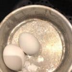 closeup: 2 eggs in a pan to soft boil eggs in air fryer basket