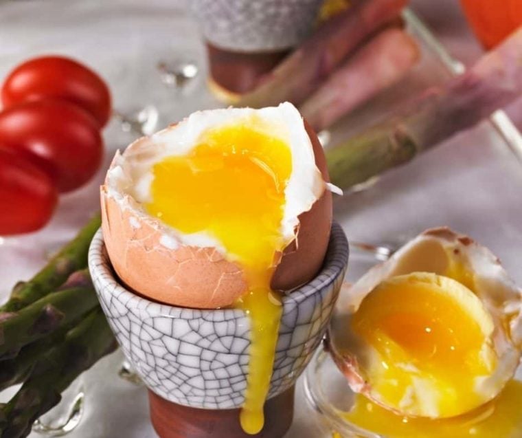 closeup: soft boiled eggs in air fryer in an egg holder with the top taken off and the runny yolk showing