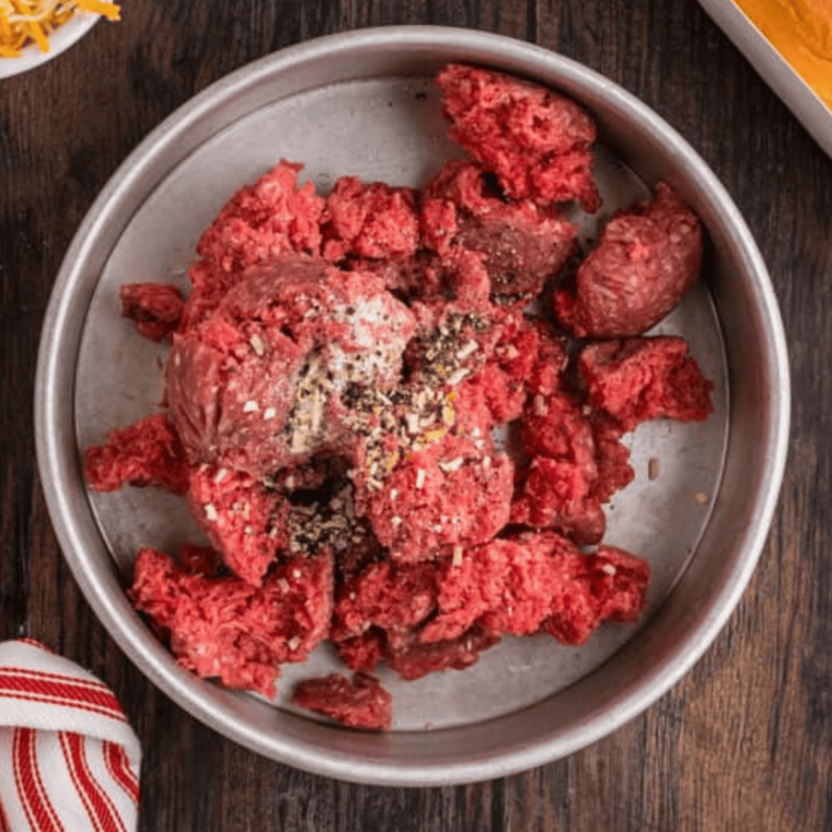 overhead: raw ground beef and seasonings in a metal baking dish