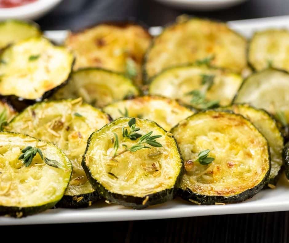 Close up of cooked zucchini disks on a white plate. 