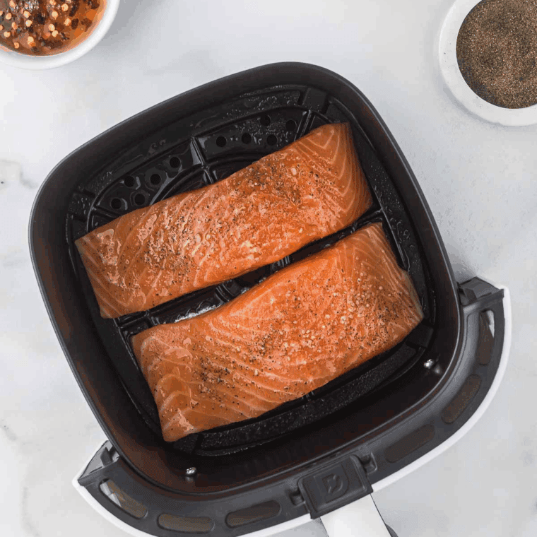 Salmon fillets cooking in air fryer until opaque and flaky