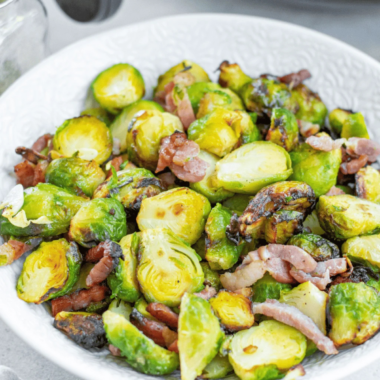 Bowl of crispy air fryer Brussels sprouts with chopped bacon and a honey-garlic glaze