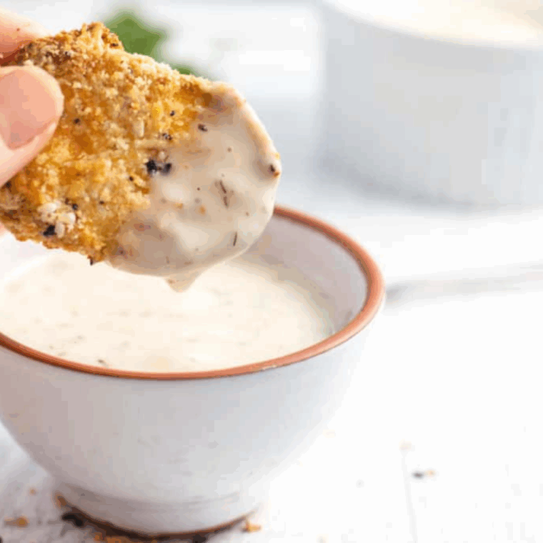 Dipping Air Fryer Everything Bagel Zucchini Chips in ranch sauce.