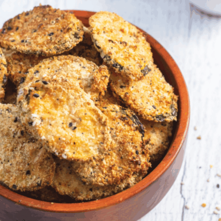 Golden air-fried zucchini chips sprinkled with everything bagel seasoning on a serving plate.