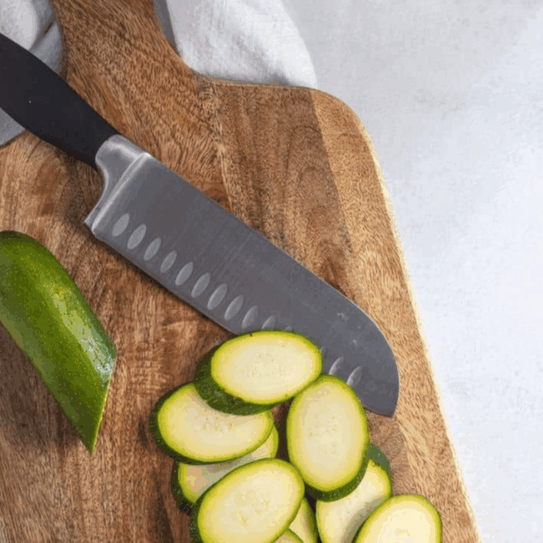 Slicing the zucchini on the cutting board.