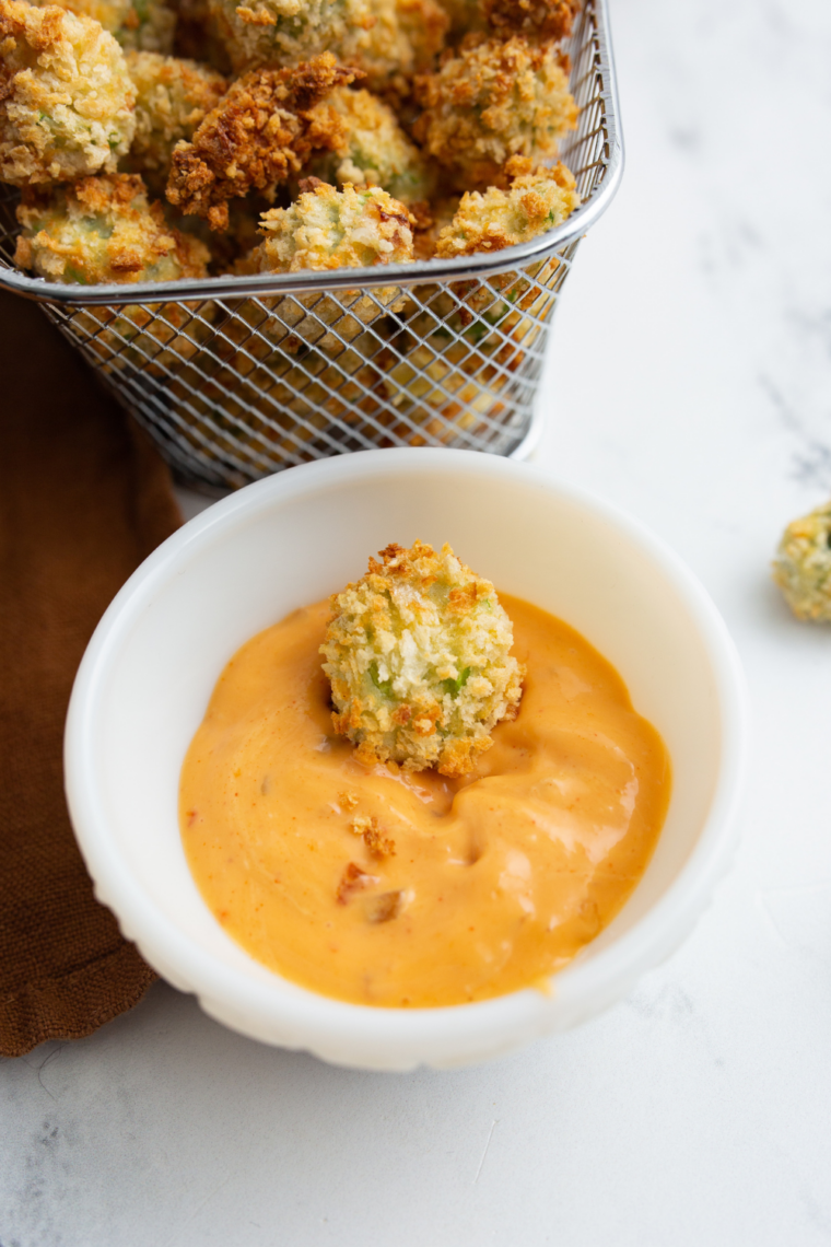 Breaded okra dipped into a bowl of creamy ranch sauce