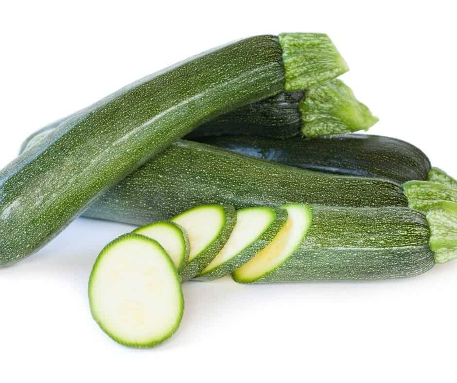 Fresh zucchini stacked with some chopped into disks. 