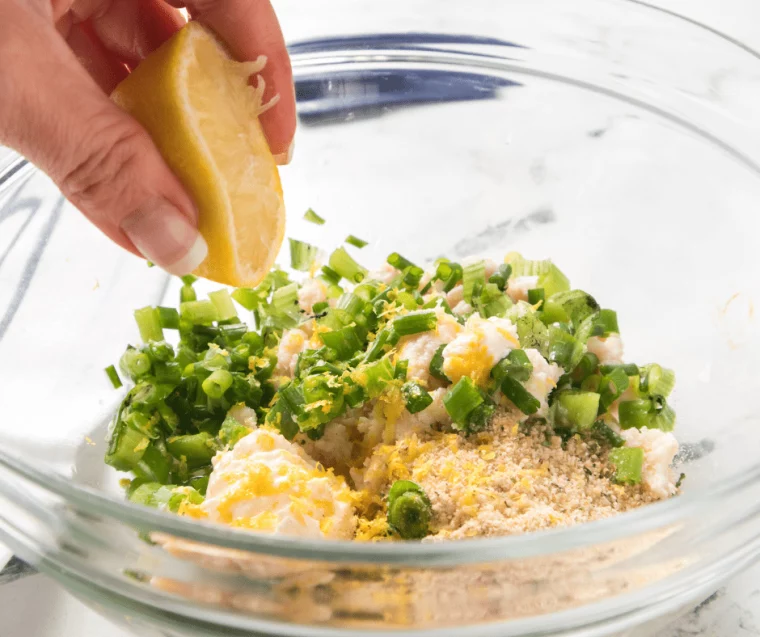Adding the final lemon juice to the crab cake mixture.