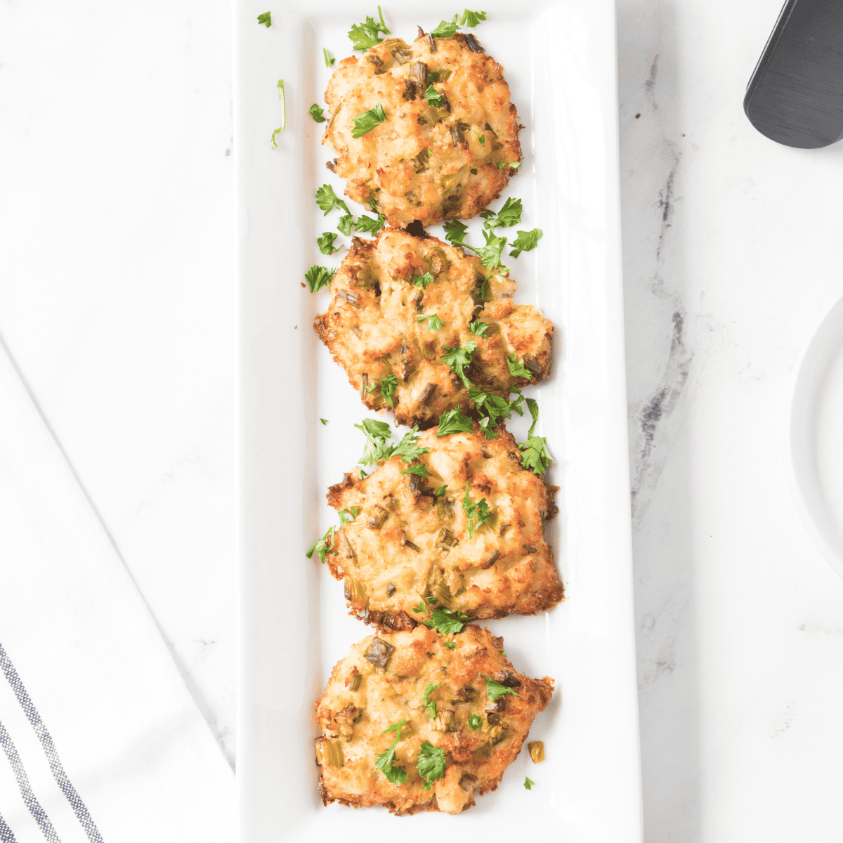 Air fryer lemon crab cakes served with lemon wedges and herbs on a white plate