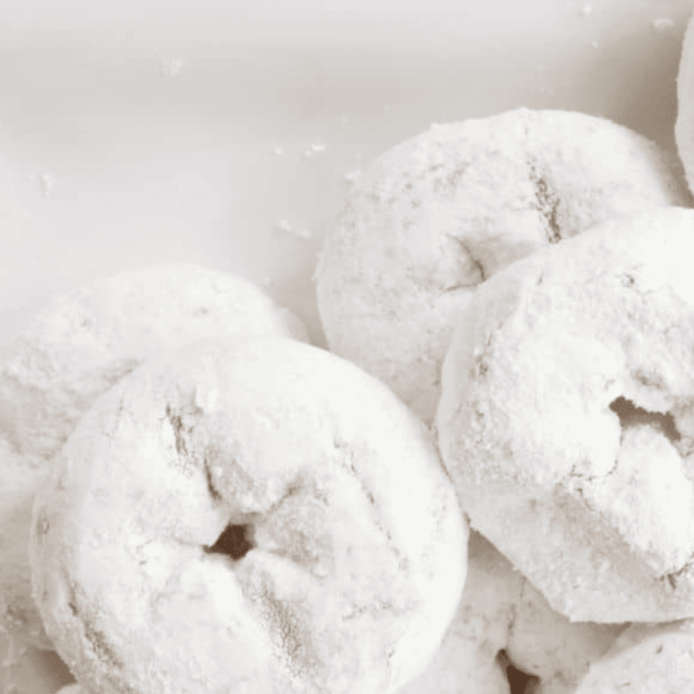 Finished Air Fryer Donuts dusted with powdered sugar on a plate.