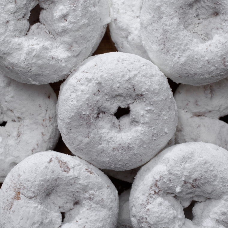 Golden brown Air Fryer donuts dusted with powdered sugar on a plate.