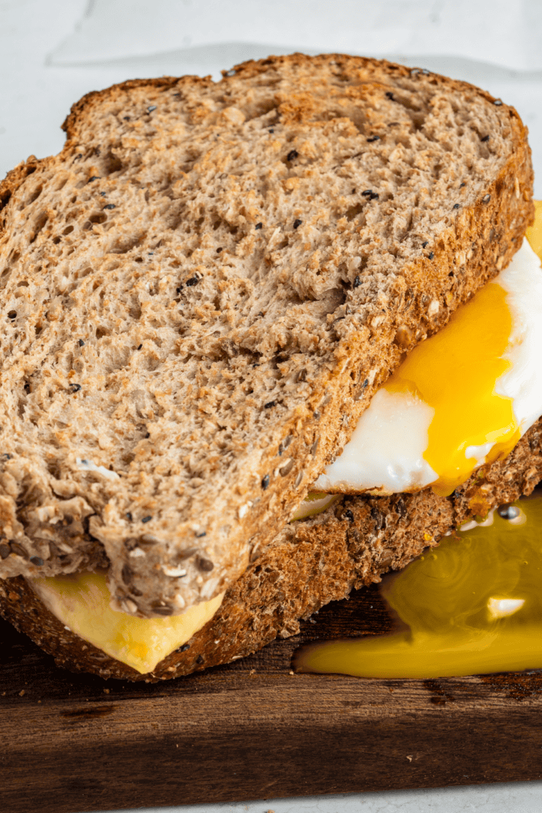 Close-up of an air fryer sausage, bacon, and egg sandwich cut in half to show the egg and cheese inside.