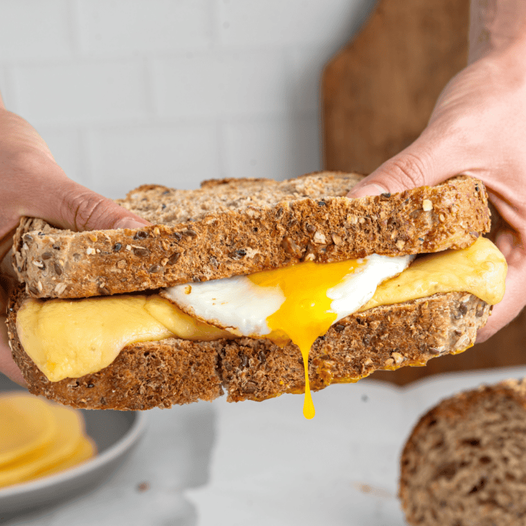 Hearty air fryer breakfast sandwich layered with crispy bacon, sausage patty, scrambled egg, and melted cheese.