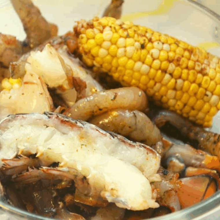 Ingredients needed for Air Fryer Seafood Boil on kitchen table in a large mixing bowl.