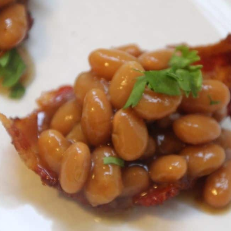 Completed bacon bowl filled with baked beans and sprinkled with fresh herbs.