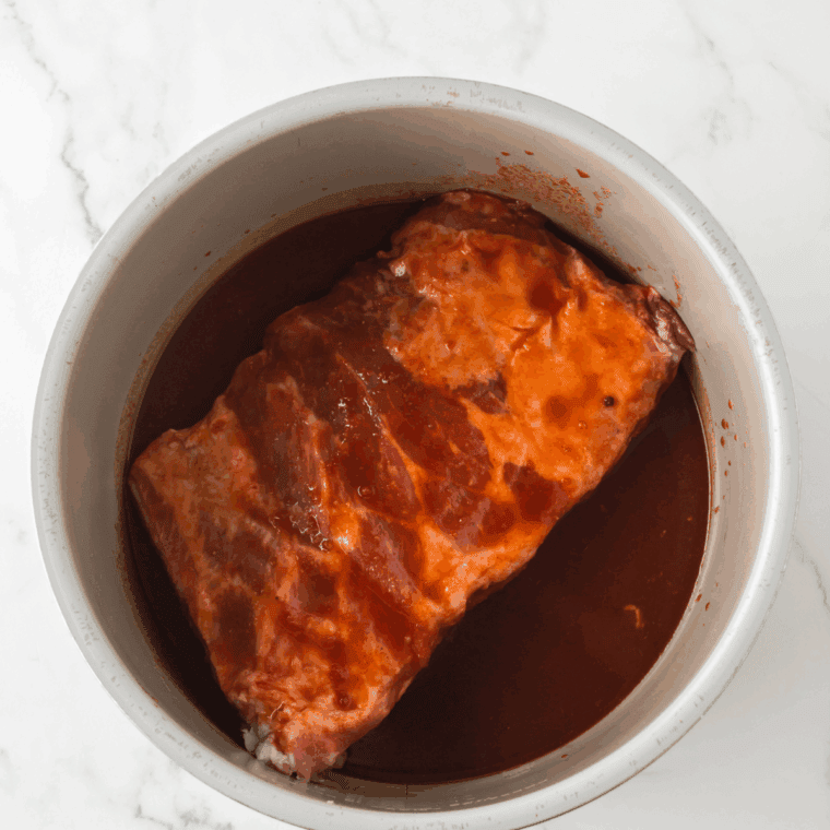 Pouring beef broth into the Instant Pot while scraping up browned bits from the bottom.