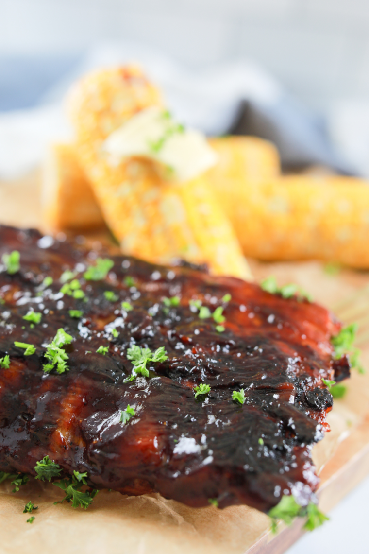 Delicious Blackstone griddle ribs with BBQ sauce, served with a side of corn.