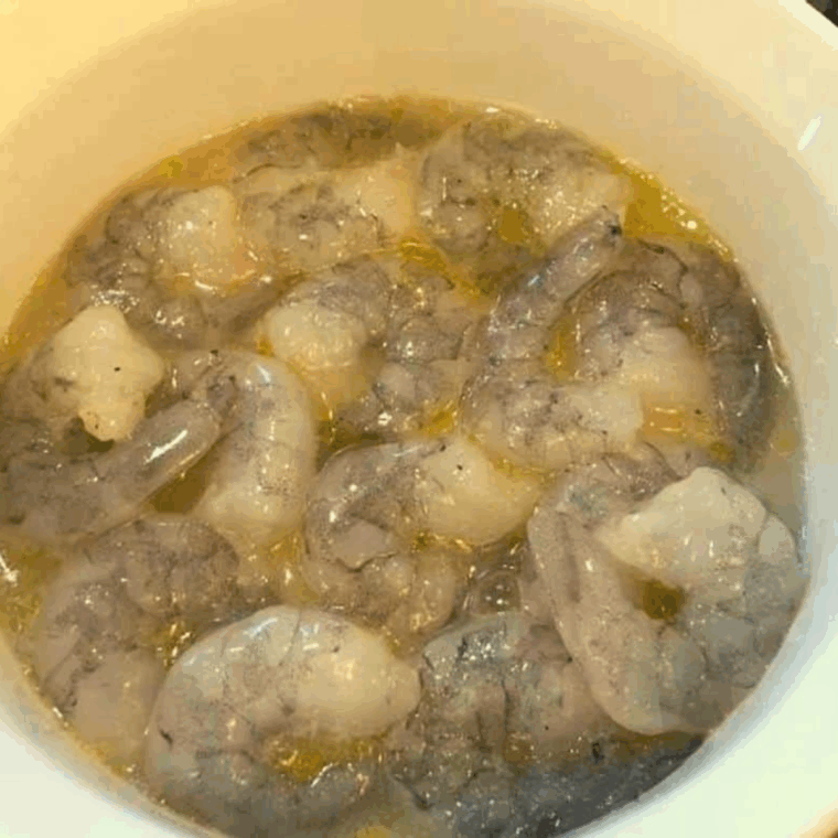 Shrimp tossed with lemon, oil, and seasoning layered in a casserole dish.