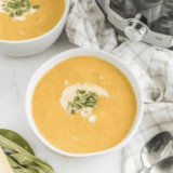 Bowl of creamy copycat Costco butternut squash soup topped with toasted pumpkin seeds and a swirl of coconut milk