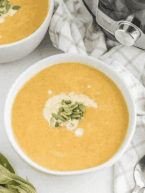 Bowl of creamy copycat Costco butternut squash soup topped with toasted pumpkin seeds and a swirl of coconut milk