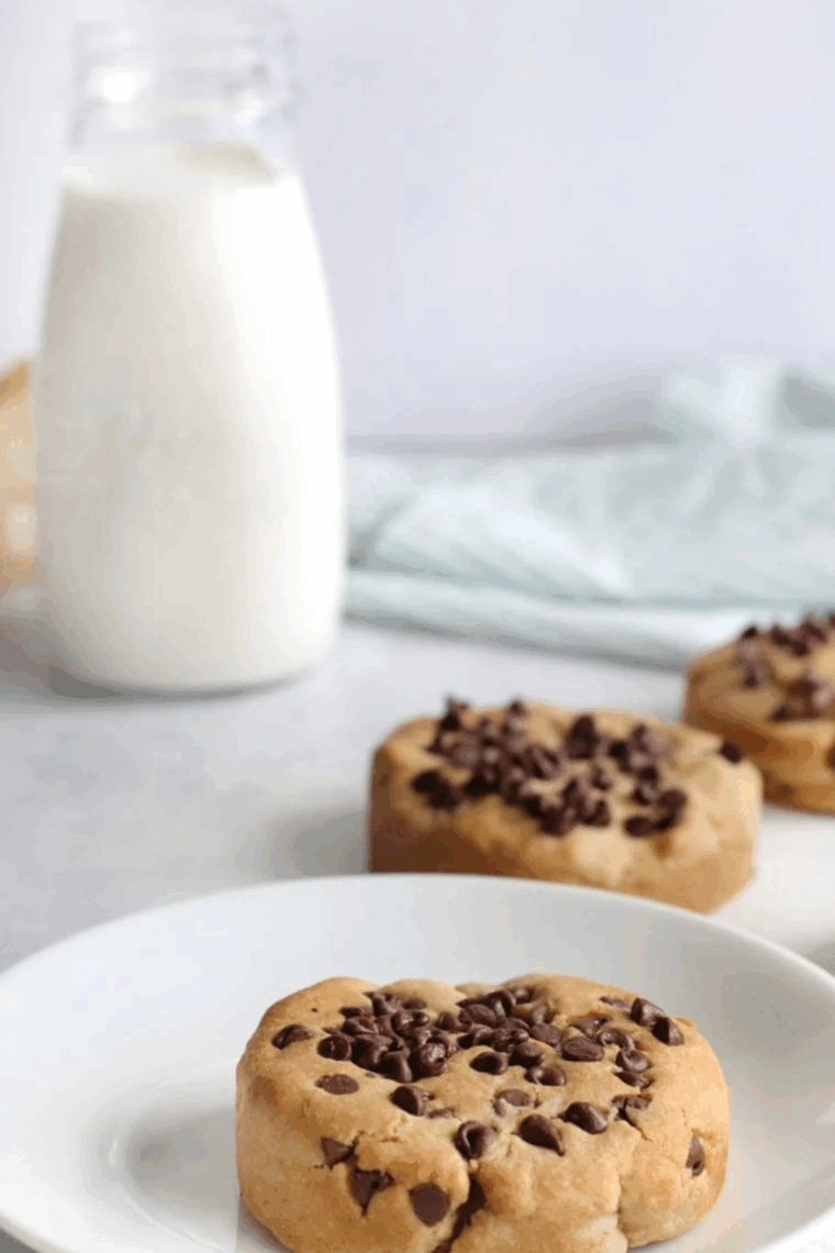 Stack of freshly baked Copycat Otis Spunkmeyer Chocolate Chip Cookies with melty chocolate chips on a cooling rack.