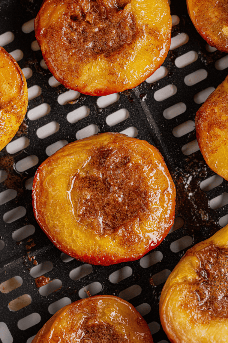 Caramelized air fryer peaches topped with brown sugar and cinnamon, served warm and golden.