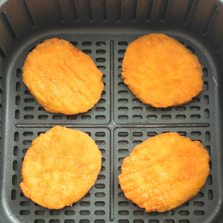 chicken patties cooking in air fryer being flipped halfway through