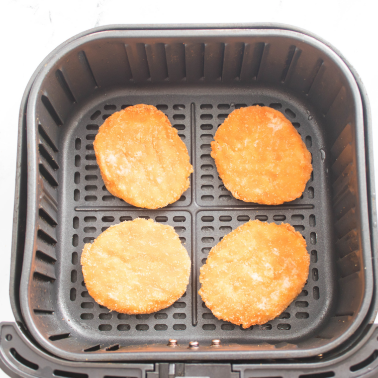 frozen chicken patties placed in air fryer basket in single layer