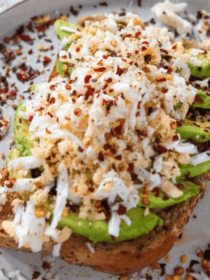 A plate of Air Fryer Grated Egg & Avocado Toast, topped with creamy avocado and a grated egg for added texture.