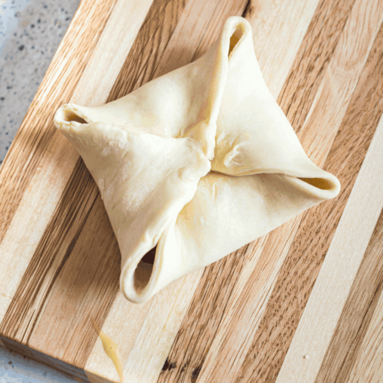 Seal the cherry turnover on a wooden cutting board.