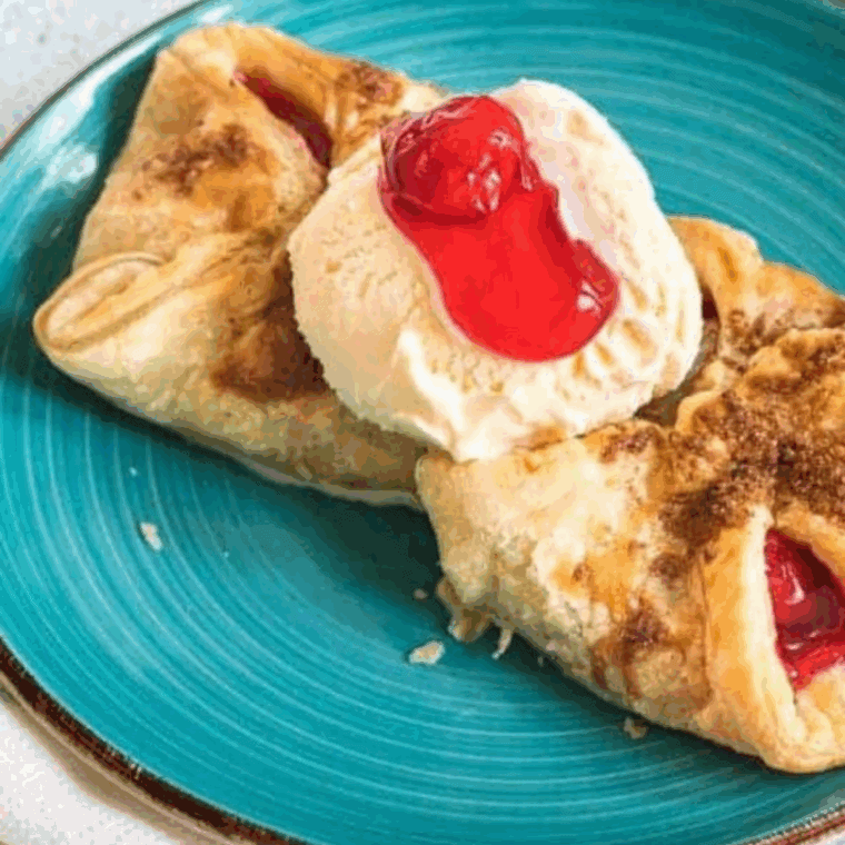 Homemade Arby’s cherry turnovers with golden pastry and icing drizzle on a plate