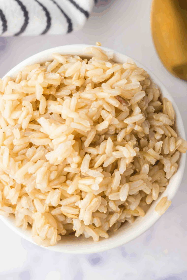 Bowl of Instant Pot Garlic Brown Rice garnished with fresh herbs