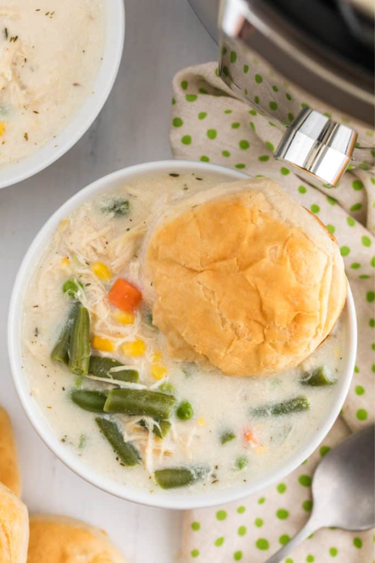 "A steaming bowl of Instant Pot Chicken Pot Pie Soup, garnished with fresh herbs and a flaky pie crust piece."