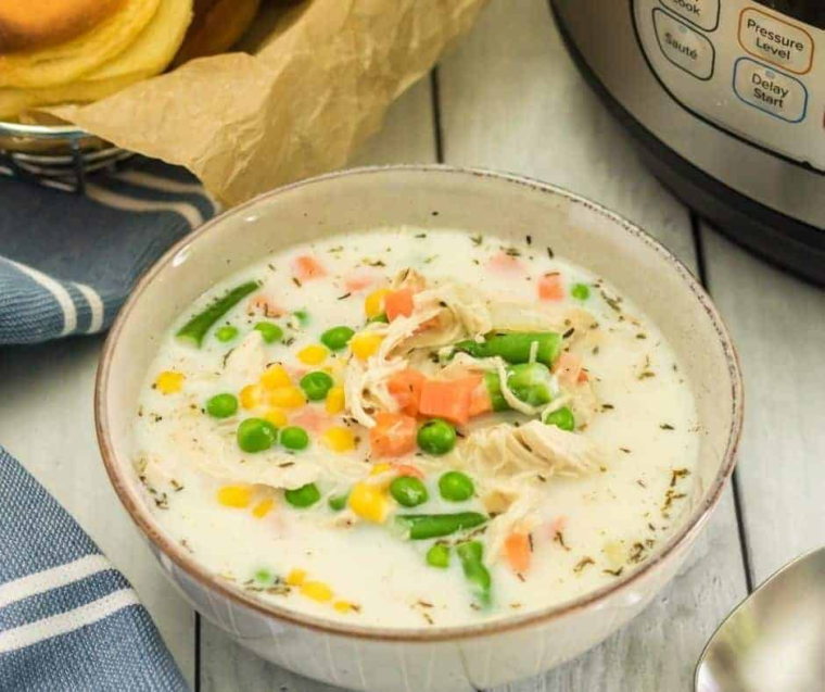 "Bowl of creamy Instant Pot Jason's Deli Chicken Pot Pie Soup with chunks of chicken, vegetables, and a biscuit topping."