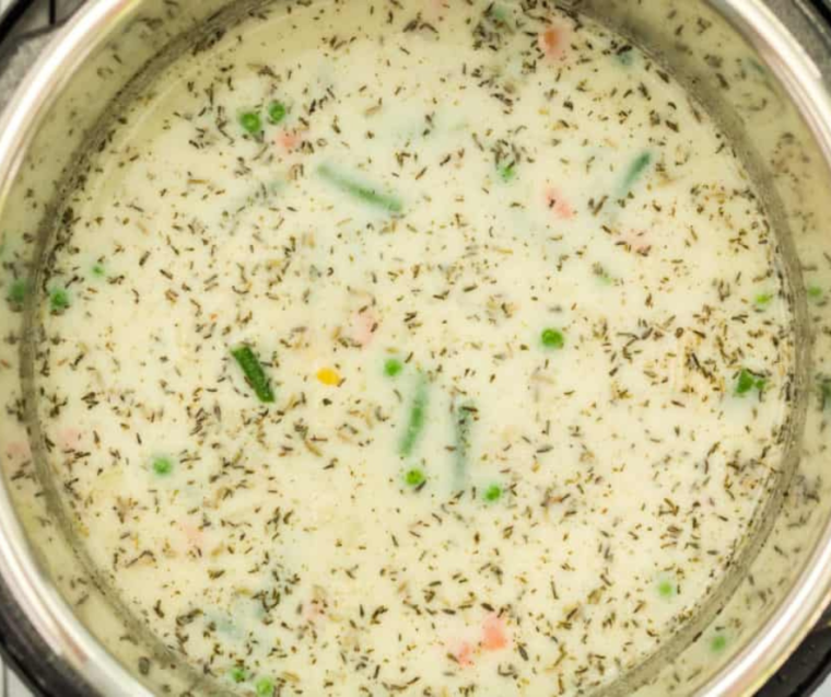 "Stirring in seasonings and cream into the Instant Pot for Chicken Pot Pie Soup, preparing for the final cooking phase."