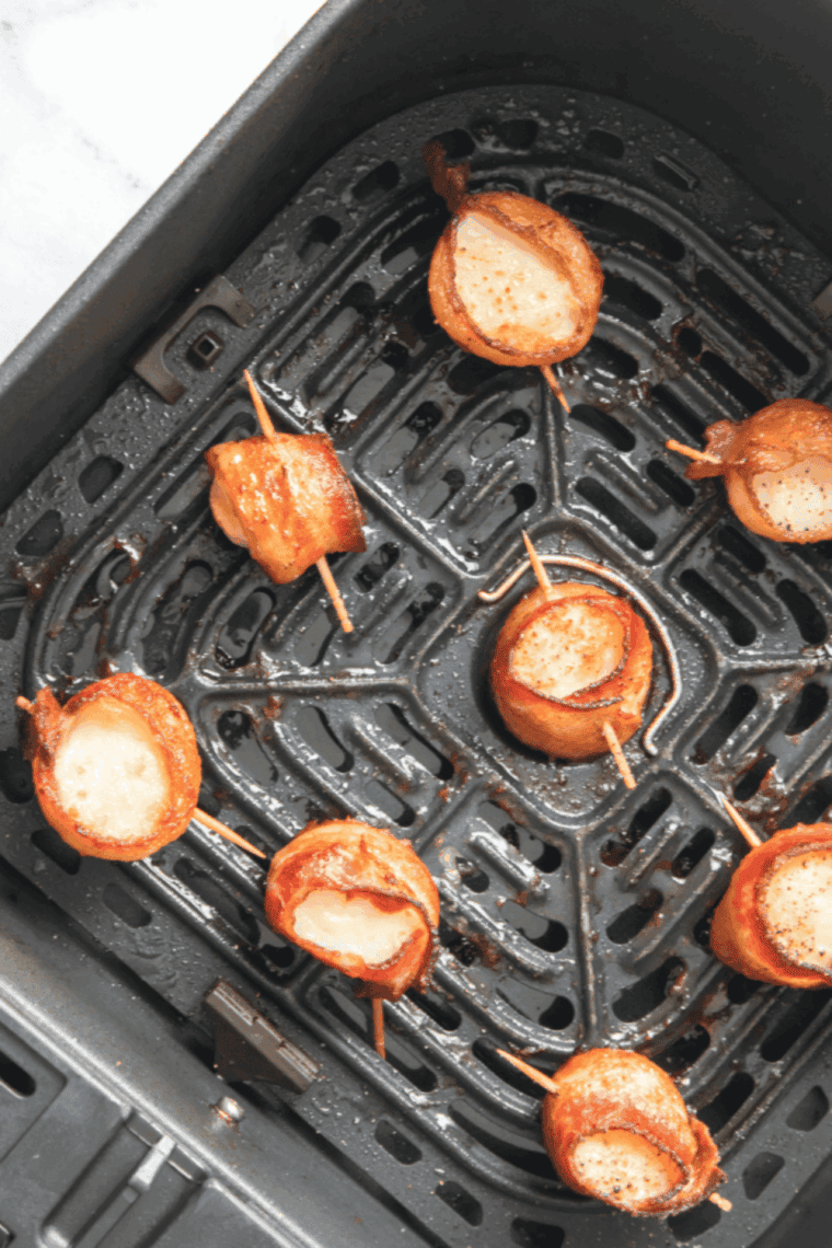 Plate of Red Lobster-style bacon wrapped scallops garnished with herbs and lemon wedges.