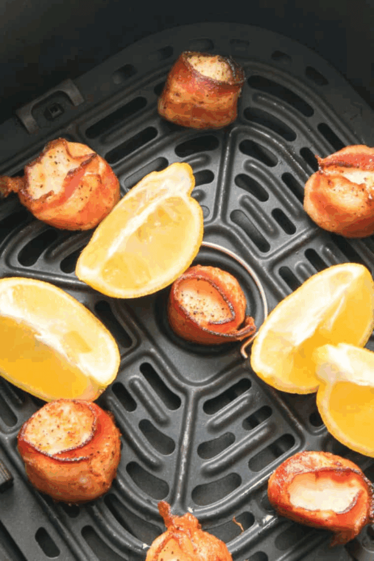 Close-up of Red Lobster-inspired bacon wrapped scallops served on a white plate with lemon wedges.