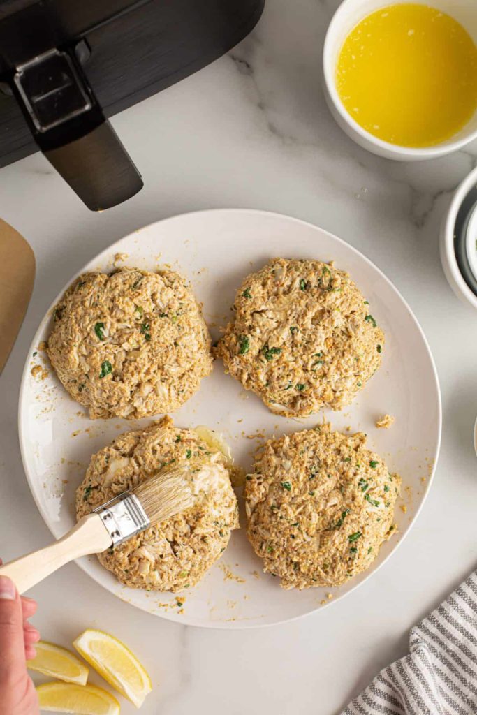 brushing butter onto crab cake patties