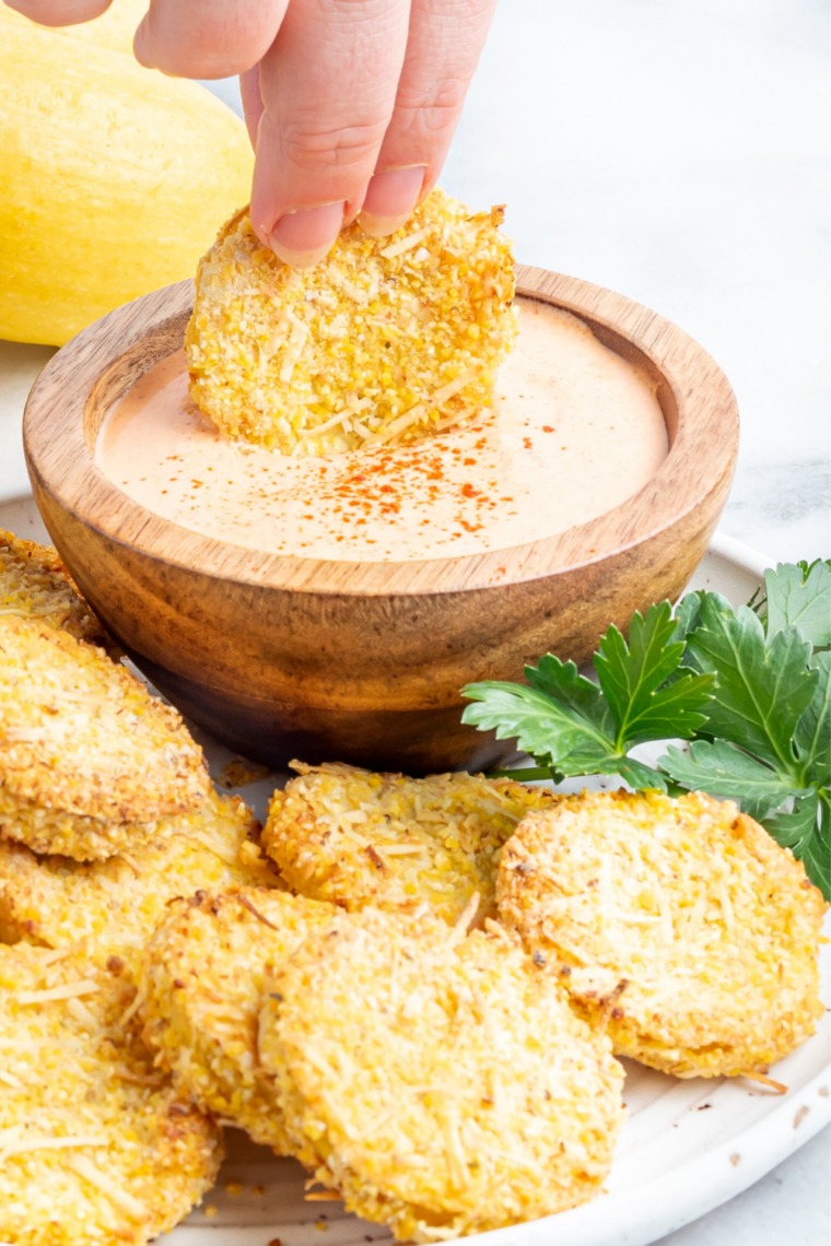 Breaded yellow squash rounds cooked golden and crisp in an air fryer basket