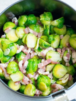 Frozen Brussels sprouts and chopped bacon cooking together in an air fryer basket