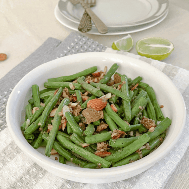 Freshly cooked crispy air fryer frozen green beans served on a white plate.