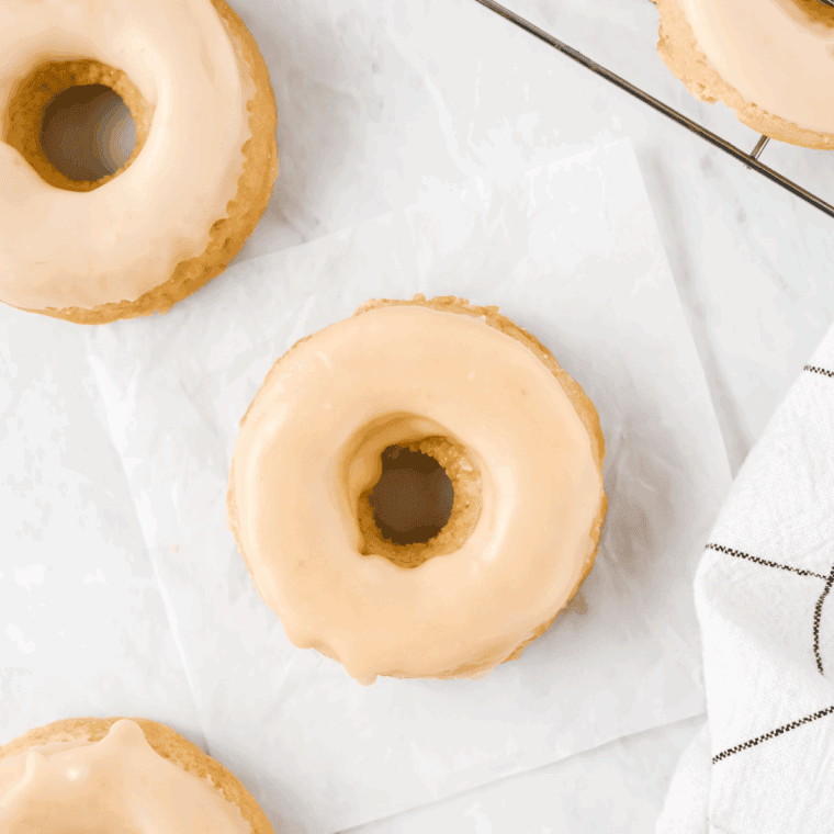 Golden air fryer donuts topped with creamy maple frosting, arranged on a cooling rack.