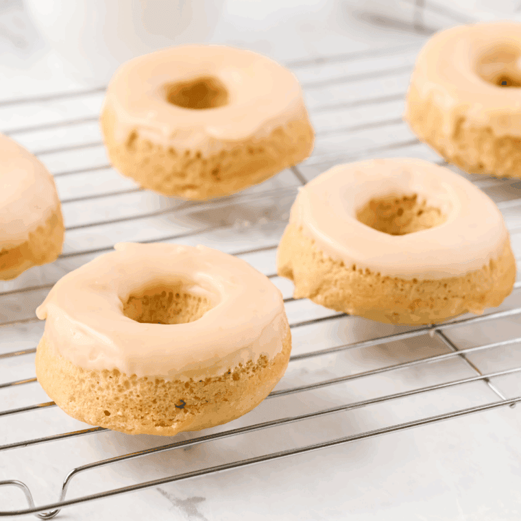 Freshly baked Air Fryer Maple Frosted Donuts on a wire rack, topped with sweet maple glaze.