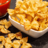 Bowl of crispy air fryer pasta chips served with marinara dipping sauce