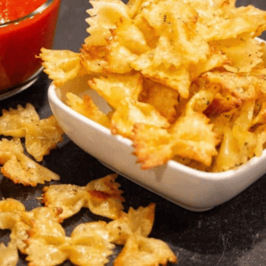 Bowl of crispy air fryer pasta chips served with marinara dipping sauce